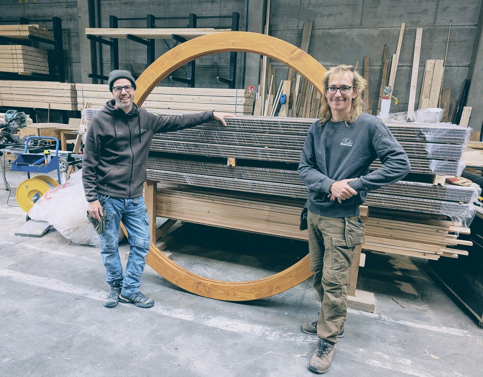 L'équipe BeYurt dans l'atelier à Hour devant une grande pièce circulaire en bois.